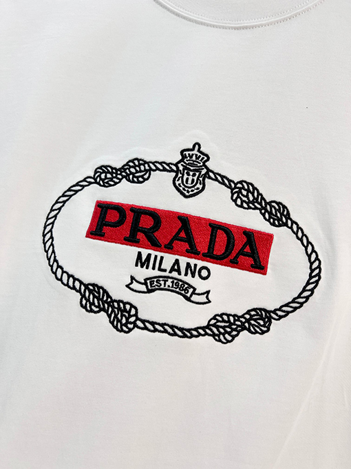 プラダ 胸に麻縄の刺繍がされた、クラシックな1986のスローガン文字ロゴ半袖Tシャツ