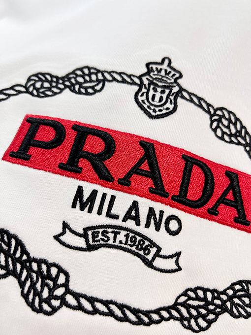 プラダ 胸に麻縄の刺繍がされた、クラシックな1986のスローガン文字ロゴ半袖Tシャツ